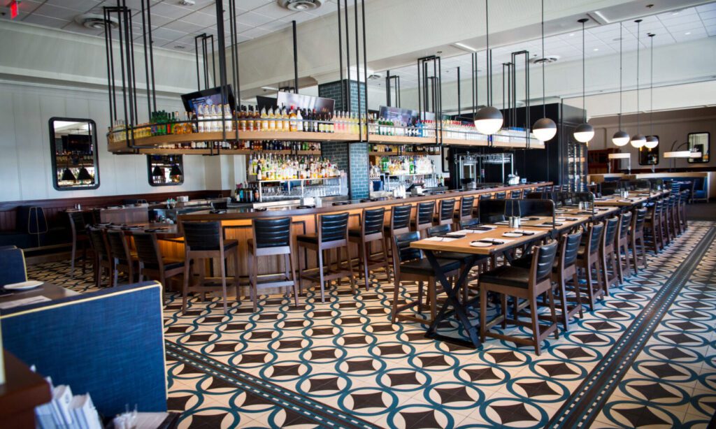 Stylish empty bar with patterned tile floor and wooden furniture.