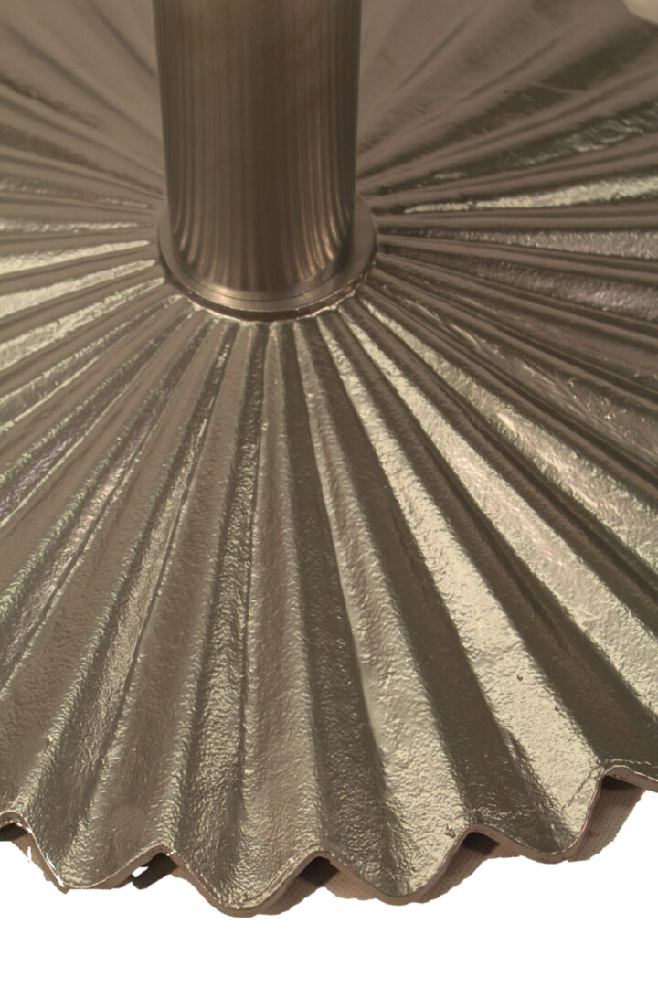 Close-up of a metallic pleated fabric with a central seam.