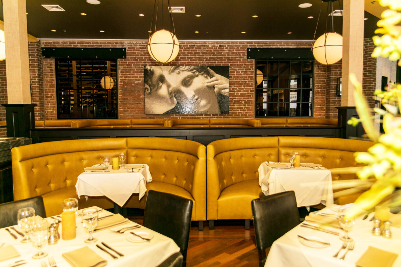 Elegant restaurant interior with cozy yellow booths and white tablecloths.