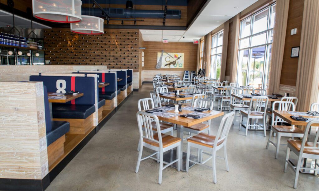Bright, modern restaurant interior with wooden tables and blue booth seating.